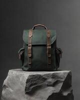A stylish green backpack with leather accents displayed on a stone pedestal photo