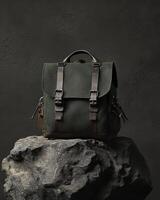 A stylish green backpack displayed on a rock, showcasing its design and functionality photo