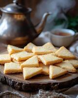 A plate of triangular cookies with a teapot and cup, creating a cozy snack scene. photo