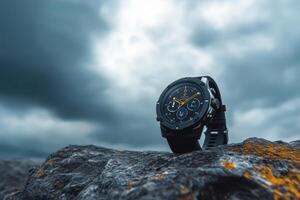 A close-up of a black watch on a rocky surface against a moody sky. photo
