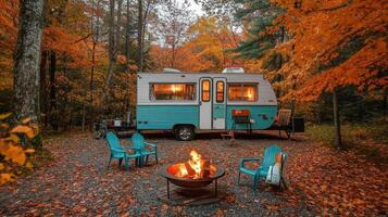 A cozy camper surrounded by vibrant autumn foliage and a fire pit for gathering. photo