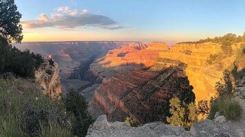 A panoramic view of the Grand Canyon at sunset, showcasing vibrant colors and rugged terrain. photo