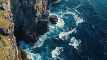 Aerial view of rugged cliffs meeting turbulent ocean waves. photo