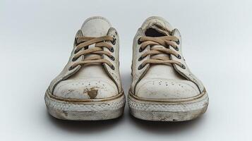 A pair of dirty white sneakers on a white surface photo