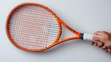 Orange Tennis Racket Held by a Hand Against a White Background photo