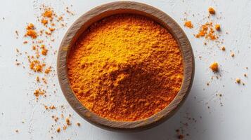 Turmeric powder in a wooden bowl on a white surface photo
