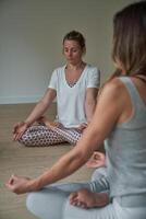 Fit females practicing Padmasana exercise in gym photo