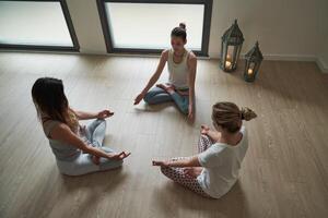 Group of females doing Padmasana exercise in spacious room photo