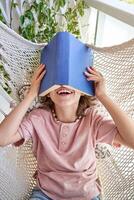 Unrecognizable boy lying in hammock with book on head photo