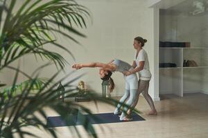 Woman doing Wheel pose with instructor in studio photo