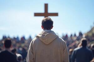 A man in a hooded jacket standing in front of a cross photo