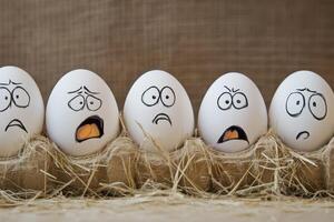 Five white eggs with faces drawn on them photo