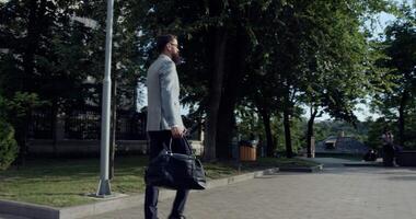 A confident businessman is walking through an urban setting, showcasing his ambition and style video