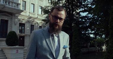 An Elegant Man Dressed in a Formal Suit with a Stylish Beard and Glasses at a Historic Location video