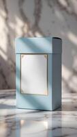 Elegant pastel-blue gift box with a decorative white label, presented on a marble surface with soft light and shadow, ideal for gifting. photo