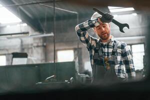 With wrench in hand. Factory ,male worker in uniform is indoors photo