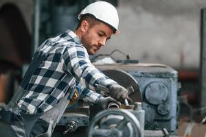 Operating ,machine. Factory male worker, in uniform is indoors photo