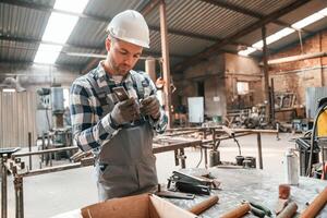 Using professional ,tools. Factory male worker in uniform is indoors photo