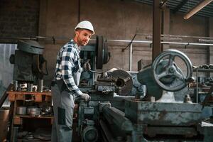 Side view.. Operating ,the machine. Factory male worker in uniform is indoors photo