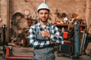 Many objects ,behind. Factory male worker in uniform is indoors photo