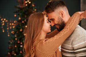 Side view.. Standing and embracing each other. Lovely young couple are celebrating New Year at home photo