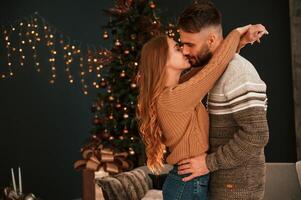Side view. .Standing and embracing each other. Lovely young couple are celebrating New Year at home photo
