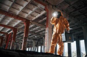 Bottom view. Man dressed in chemical protection suit in the ruins of the post apocalyptic building photo