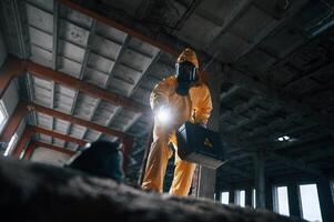 Looking below at the object. Man ,dressed in chemical protection suit in the ruins of the post apocalyptic building photo
