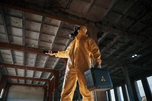 Using ,the flashlight. Man dressed in chemical, protection suit in the ruins of the post apocalyptic building photo
