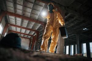 Looking below at the object. Man dressed in ,,chemical protection suit in the ruins of the post apocalyptic building photo