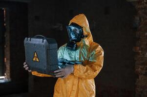 Frightened, scientist is with radioactive materials. Man dressed in chemical protection suit in the ruins of the post apocalyptic building photo