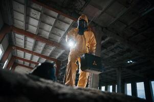 Looking below ,at the object. Man dressed in chemical protection suit in the ruins of the post apocalyptic building photo