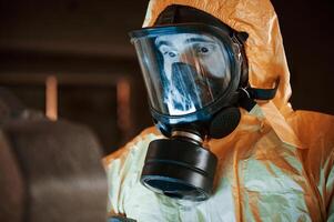 Frightened ,scientist is with radioactive materials. Man dressed in chemical protection suit in the ruins of the post apocalyptic building photo