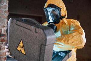 Frightened scientist is with radioactive materials. Man dressed in chemical protection suit in the ruins of the post apocalyptic building photo