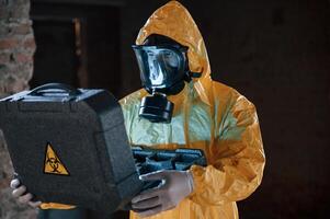 Frightened, scientist, is with radioactive materials. Man dressed in chemical protection suit in the ruins of the post apocalyptic building photo