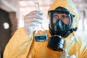 Frightened scientist, is with radioactive materials. Man dressed in chemical protection suit in the ruins of the post apocalyptic building photo