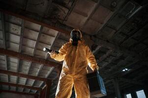 Using the flashlight. Man dressed,, in chemical protection suit in the ruins of the post apocalyptic building photo