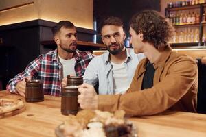 Having a ,conversation. Three friends are in the bar drinking beer and having a good time photo