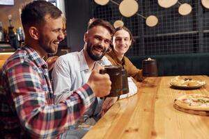 Sitting and smiling. Three ,friends are in the bar ,drinking beer and having a good time photo