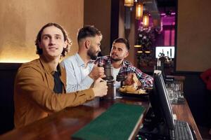 Three friends are in the bar drinking ,beer and, having a good time photo