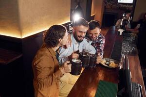Sitting by, the table.. Three, friends are in the bar drinking beer and having a good time photo