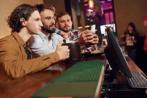 Sitting by the table. Three, friends are in the bar,drinking beer and having a good time photo
