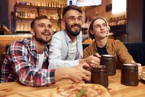 Front view. Soccer fans.. Three friends are in the bar drinking beer and having a good time photo