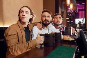 Three friends are in the bar, drinking beer ,and having a good time photo