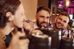 Sitting by the table.. Three, friends are in the bar drinking beer and having a good time photo