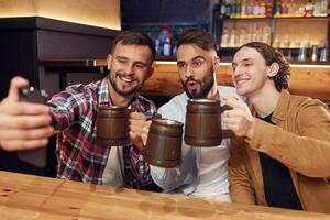 Making selfie. Three friends are ,in the bar drinking ,beer and having a good time photo