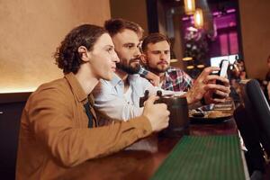 Sitting by ,the table. Three friends are in the bar drinking beer and having a good time photo
