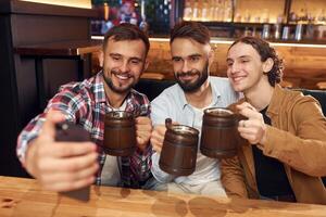 Making, selfie. Three friends are in the bar drinking beer and having a good time photo
