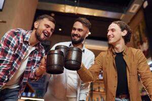 Knocking, the mugs. Three friends are in the bar drinking beer and having a good time photo