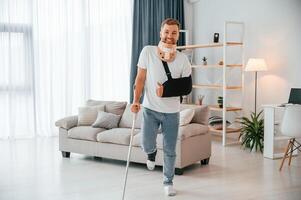 Standing and smiling.. Man with ,crutches is at home indoors. Having injuries photo